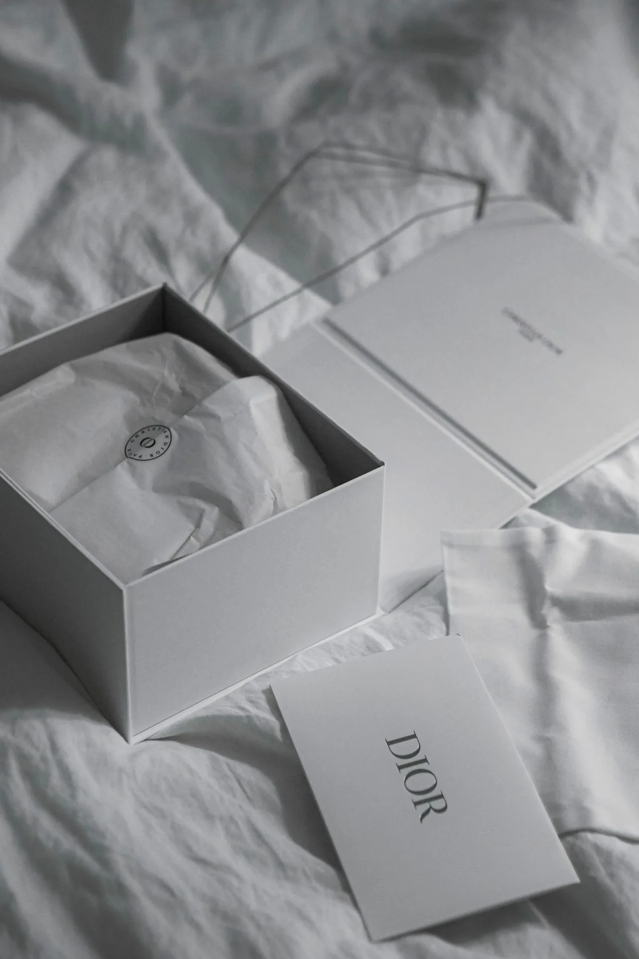 Weiße Dior Geschenkbox auf Bett mit Seidenpapier